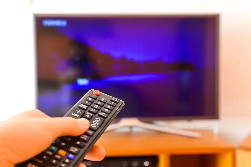 tv with hand holding remote